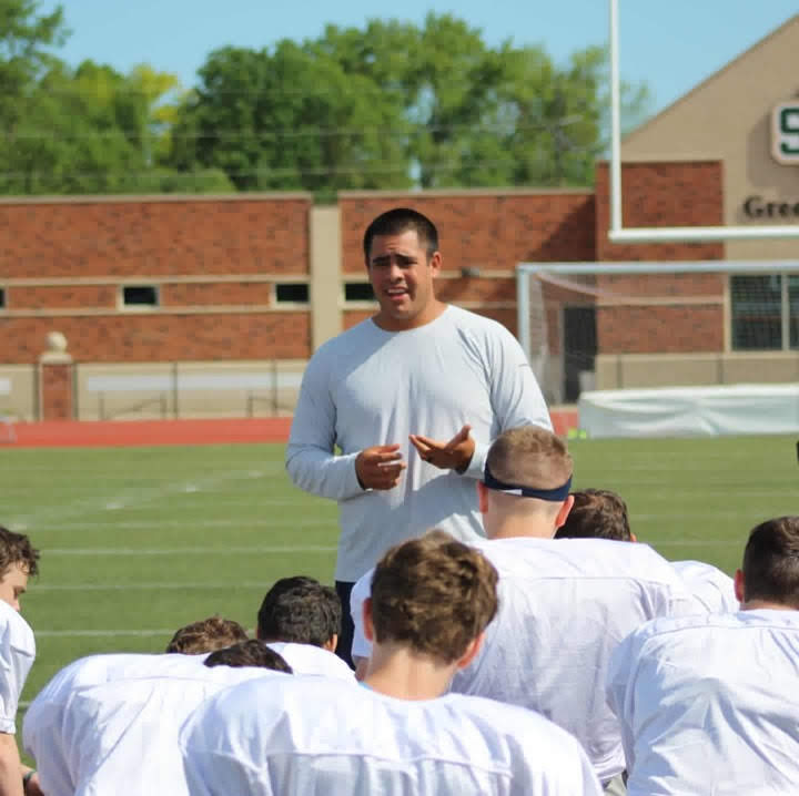 Coach teaching a group of young football players on the field