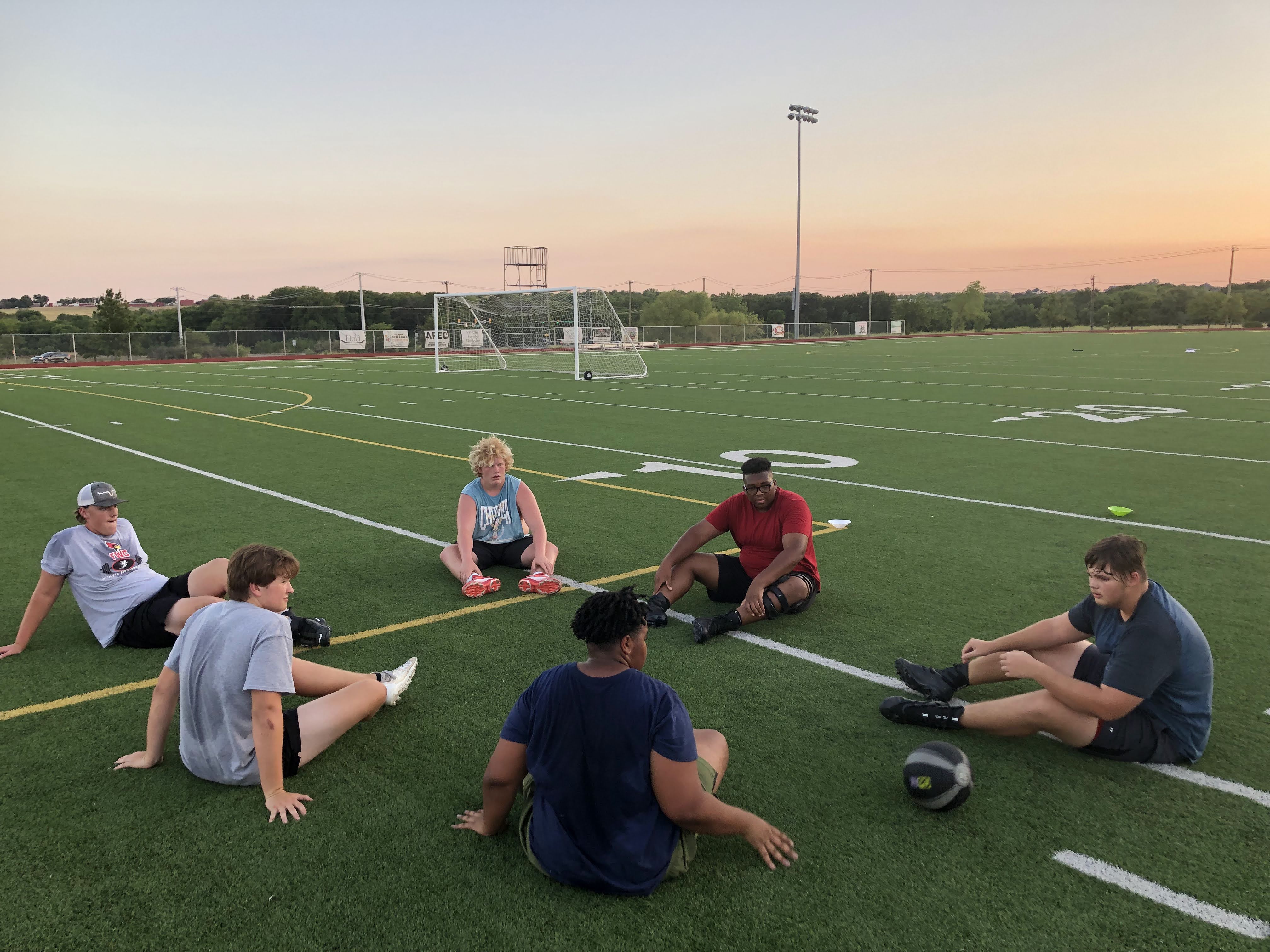Young athletes working together in a circle on a football field